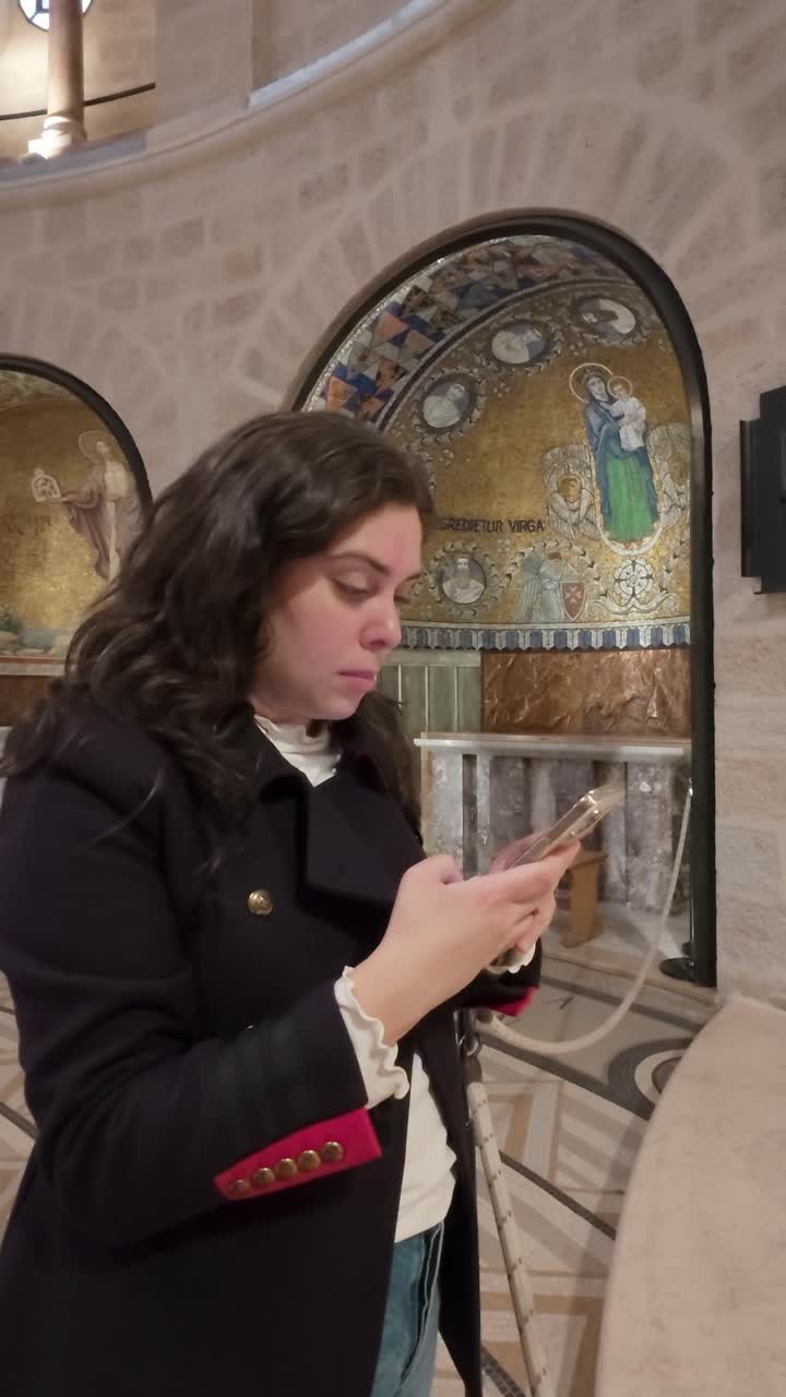 Mladá žena používající chytrý telefon v Opatství Zesnutí Panny Marie, Jeruzalém. Zpomalený záběr