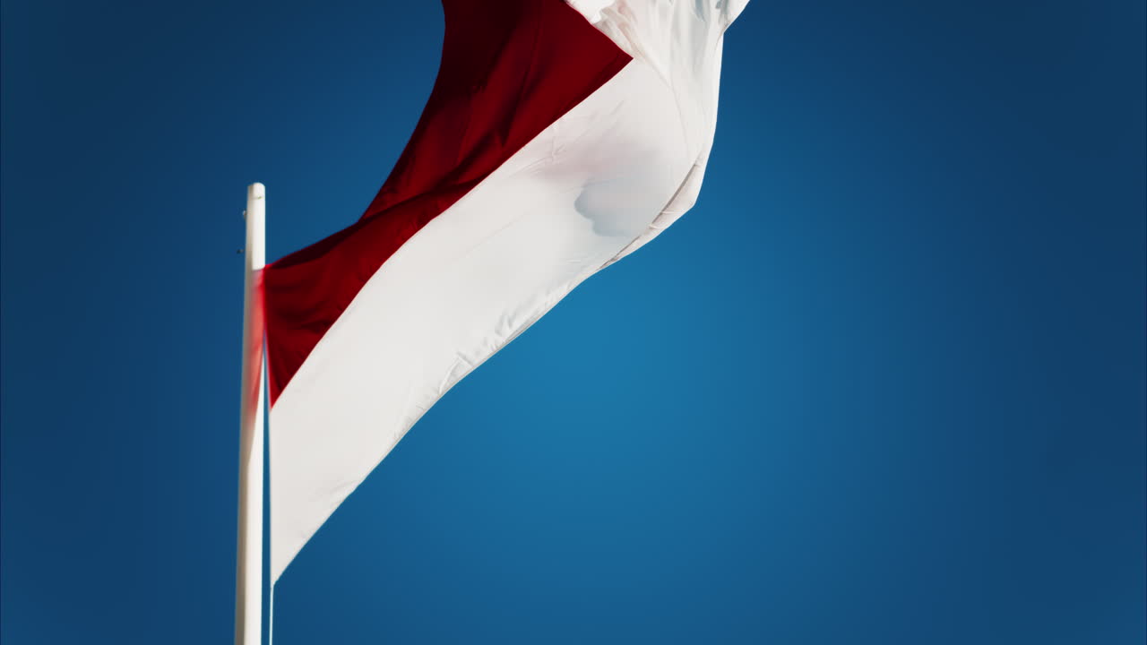 The flag of Monaco waving with the blue sky on the background