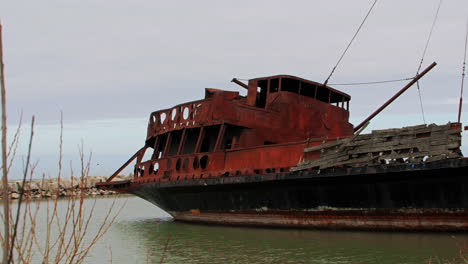 Rostiges-Rotes-Schiffswrack-Steckte-Im-Seichten-Grünen-Wasser-Fest