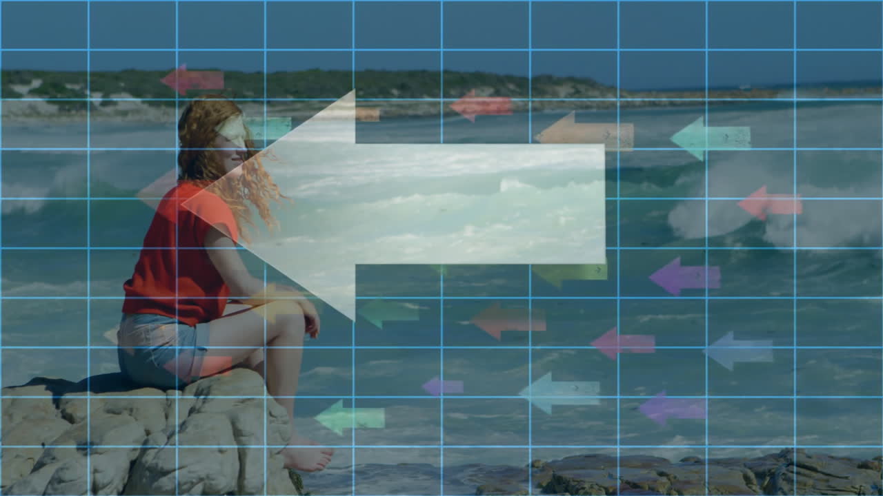 Woman sitting on rocks by ocean with digital grid overlay animation