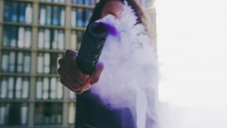 Fashionable-young-woman-on-urban-rooftop-using-a-smoke-grenade