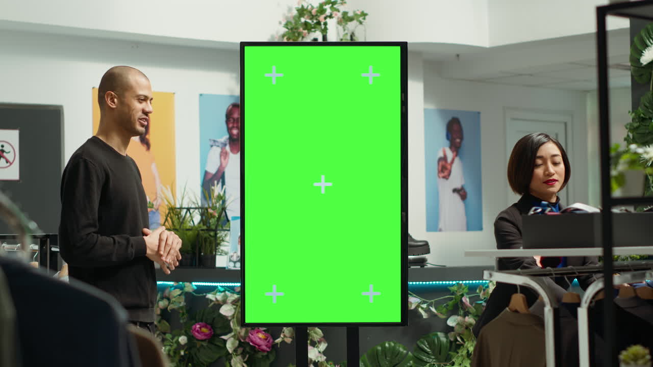 고객이 옷 가게에서 녹색 스크린 디스플레이와 상호 작용합니다.