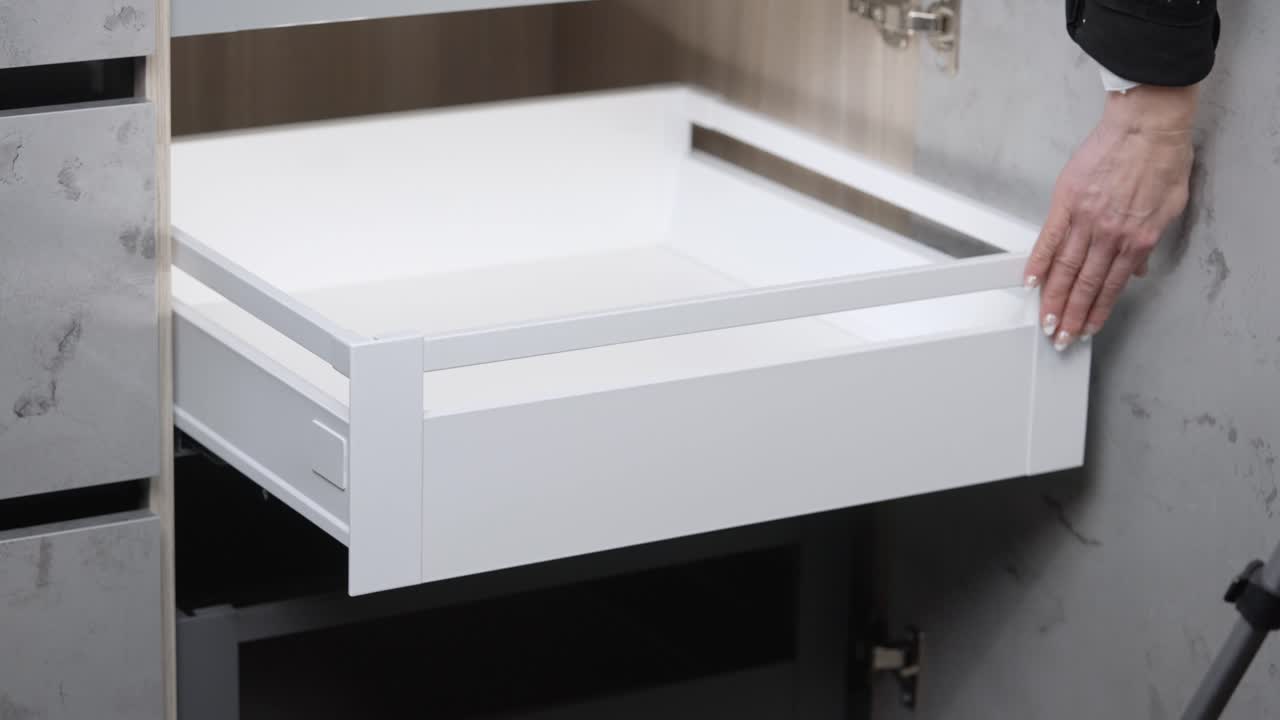 손톱을 칠한 여성이 캐비닛 서랍을 열고 닫습니다.