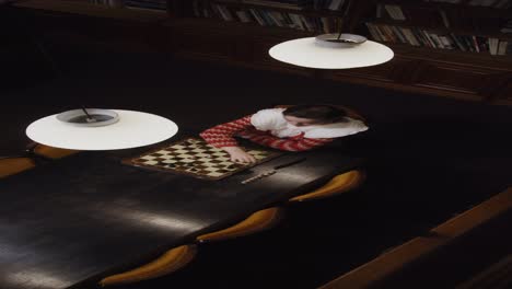 mujer jugando al ajedrez en una biblioteca