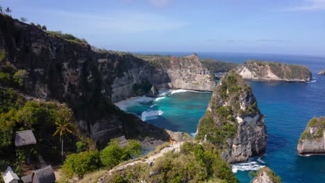 aerial push-out of sunlit seaside cliffs at nusa penida, indonesia