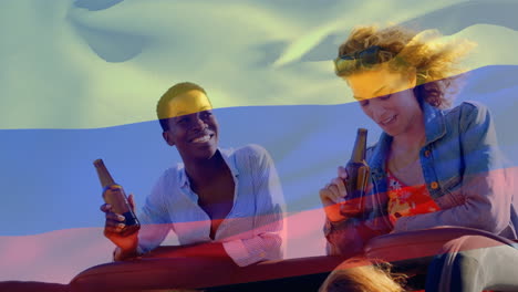 video compuesto de agitar la bandera de colombia sobre dos chicas diversas bebiendo cervezas y hablando en el coche