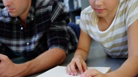 Schulmädchen-Liegt-Auf-Dem-Boden-Und-Liest-Ein-Buch-Im-Klassenzimmer