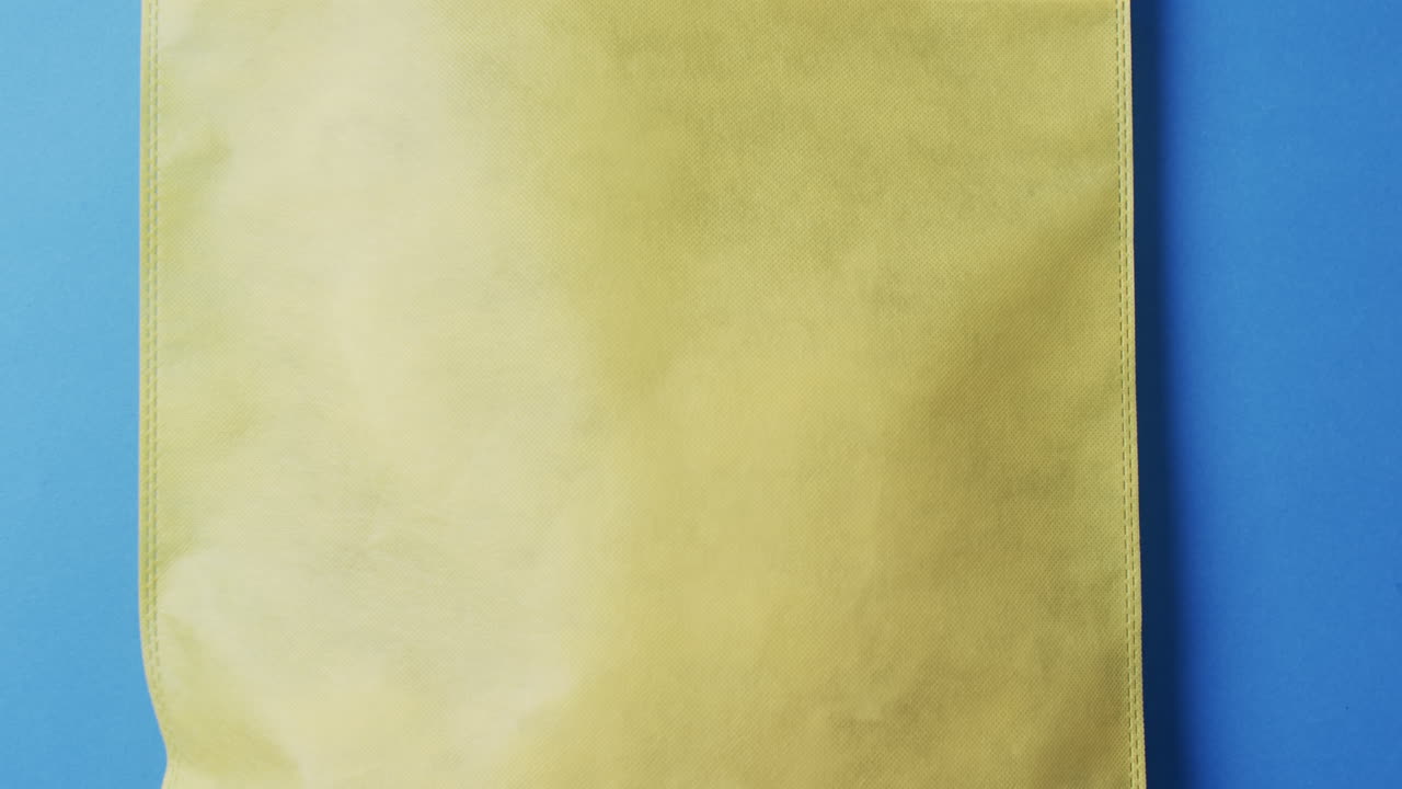 파란색 배경에 복사 공간이 있는 노란색 캔버스 가방의 비디오