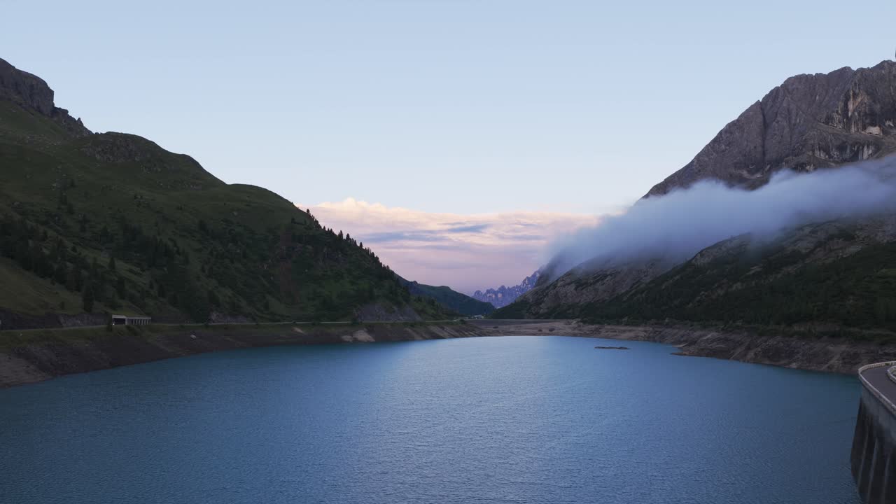 Fedaia Lake at dusk, Marmolada mountain, and misty clouds in Dolomites, Italy. Aerial drone, copy space
