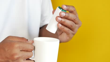 person adding sugar to a cup of coffee or tea