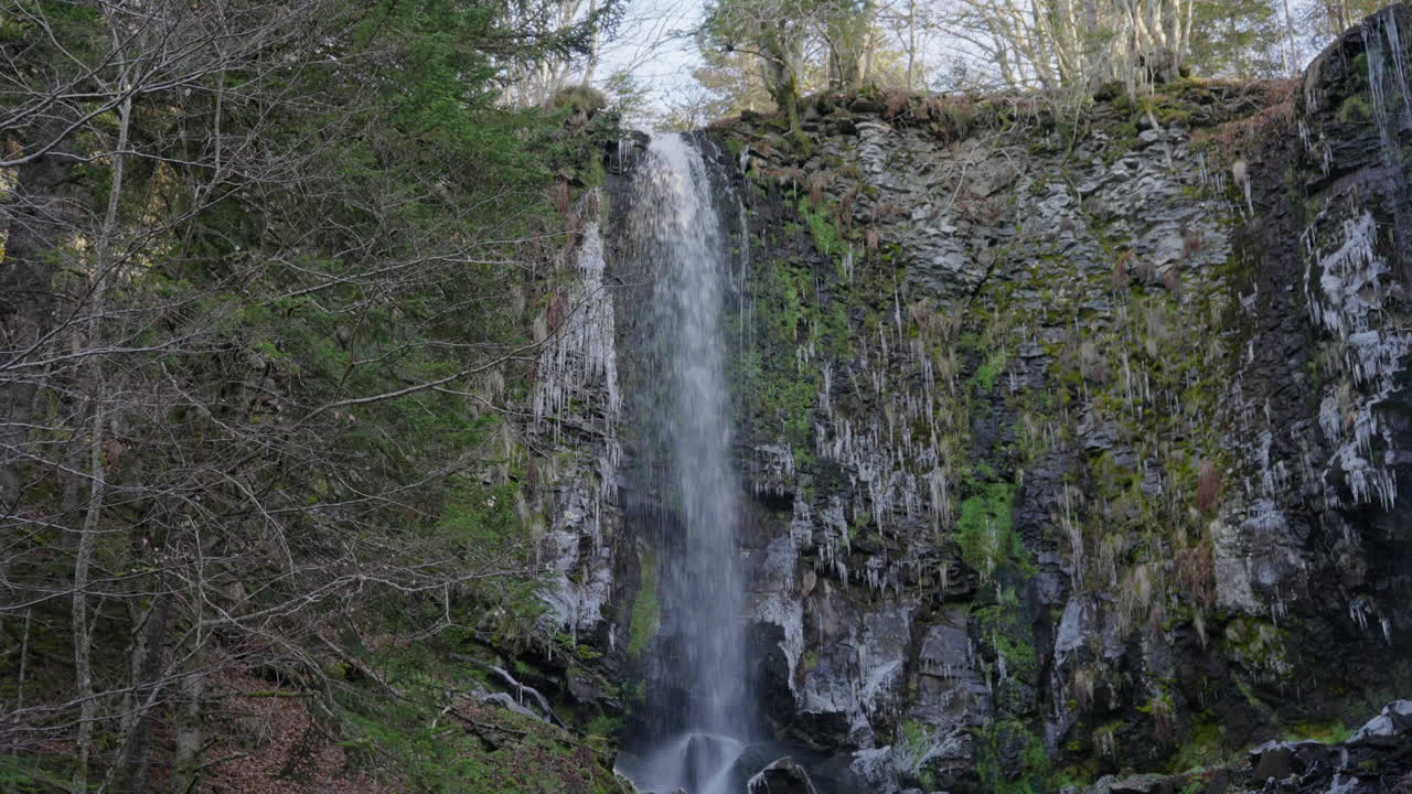 Wide shot of a small waterfall in France, in a forest.