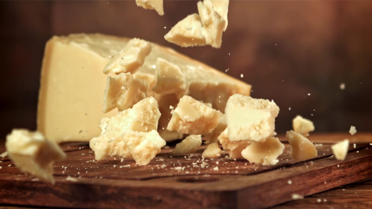Slow motion av parmesanost som smulas sönder på en träbräda