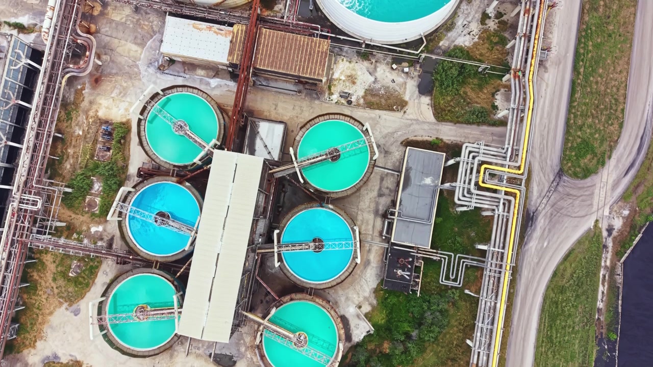Water treatment facility shows large round tanks and pipelines in a green area during daytime