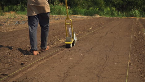 Amante-De-La-Naturaleza-Descalzo-Usando-Una-Sembradora-Para-Plantar-Verduras-Orgánicas-En-Una-Granja-Local,-Aún-Tiro