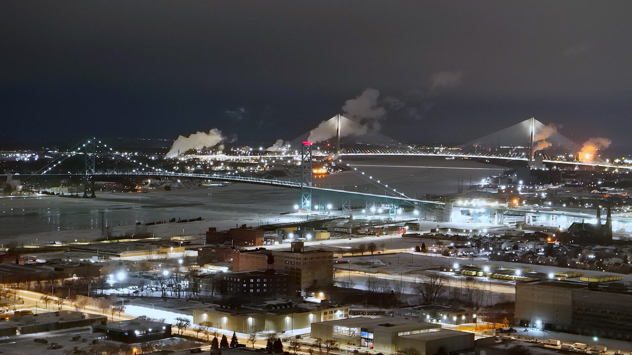 Ambassador Bridge and Gordie Howe International Bridge spanning Detroit River, connecting Detroit and Windsor, Michigan, USA in aerial view on winter night