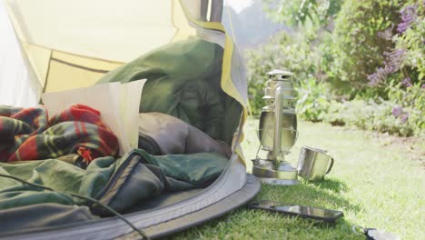 Close-up-of-yellow-tent-with-blankets-and-pillows-in-sunny-garden