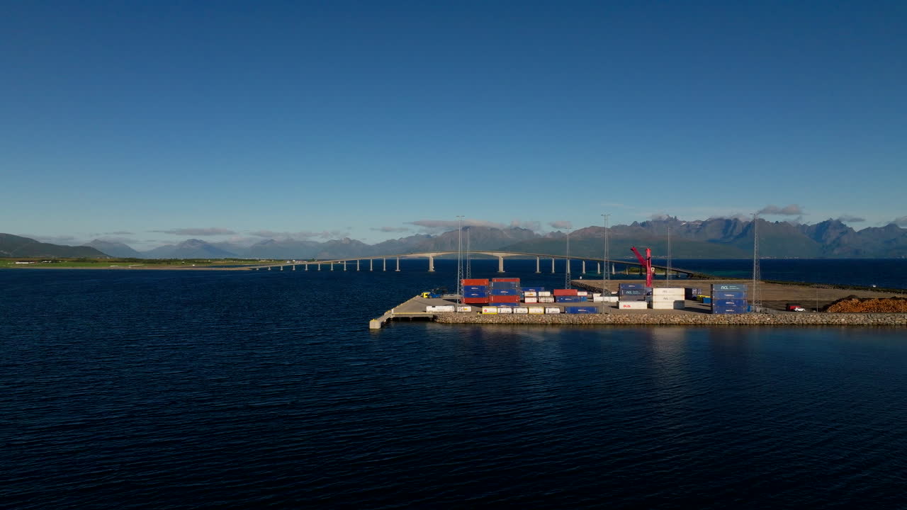 Industrial port in Stokmarknes, Norway, shipping containers on dock with Hadsel Bridge in background. Aerial drone, copy space