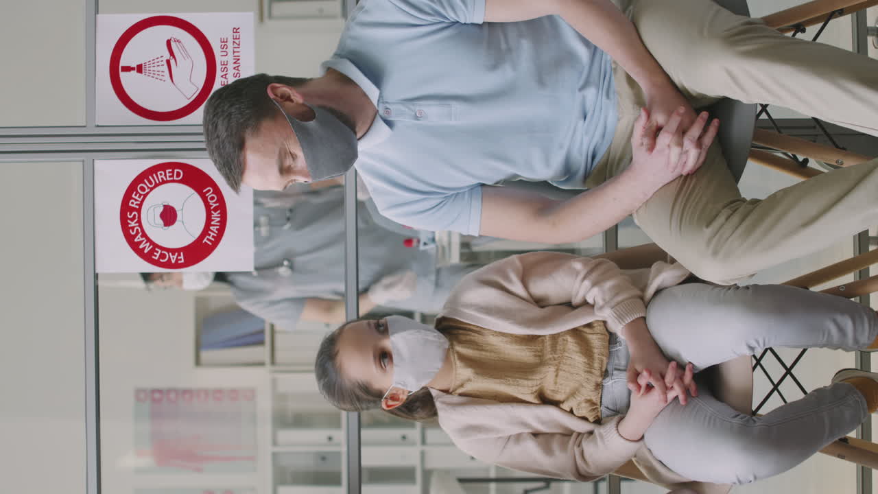 Father And Daughter Talking In Hospital Queue