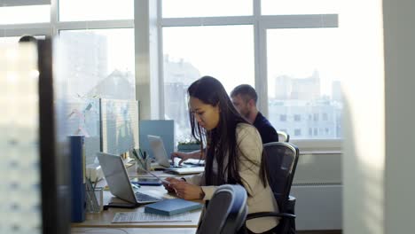 joven asiática trabajando con colegas en una oficina de espacio abierto