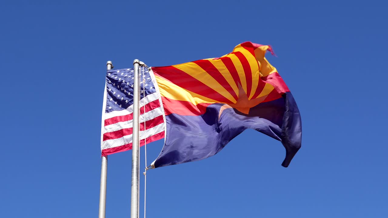 American and Arizona Flags Waving Against a Clear Blue Sky