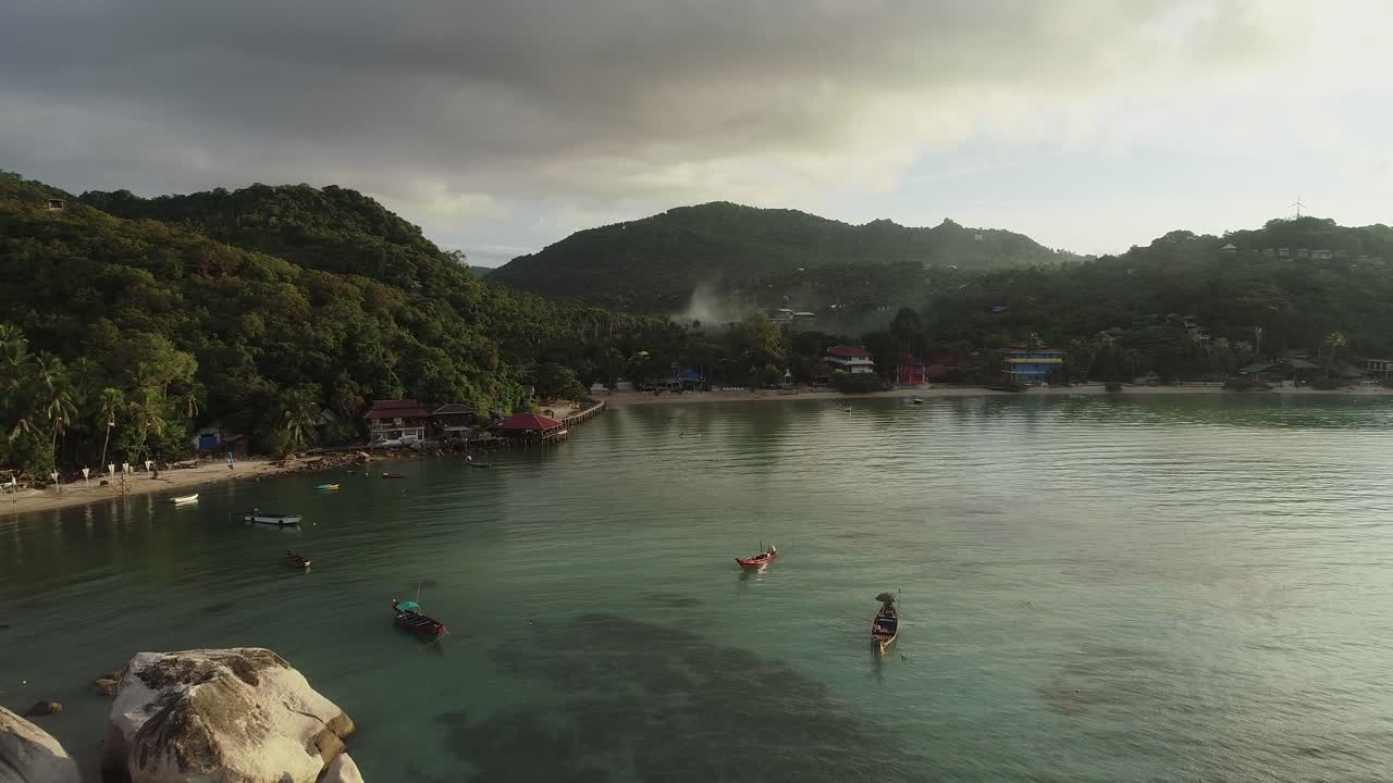 vista aérea de una playa tropical con barcos y un pequeño pueblo en el fondo