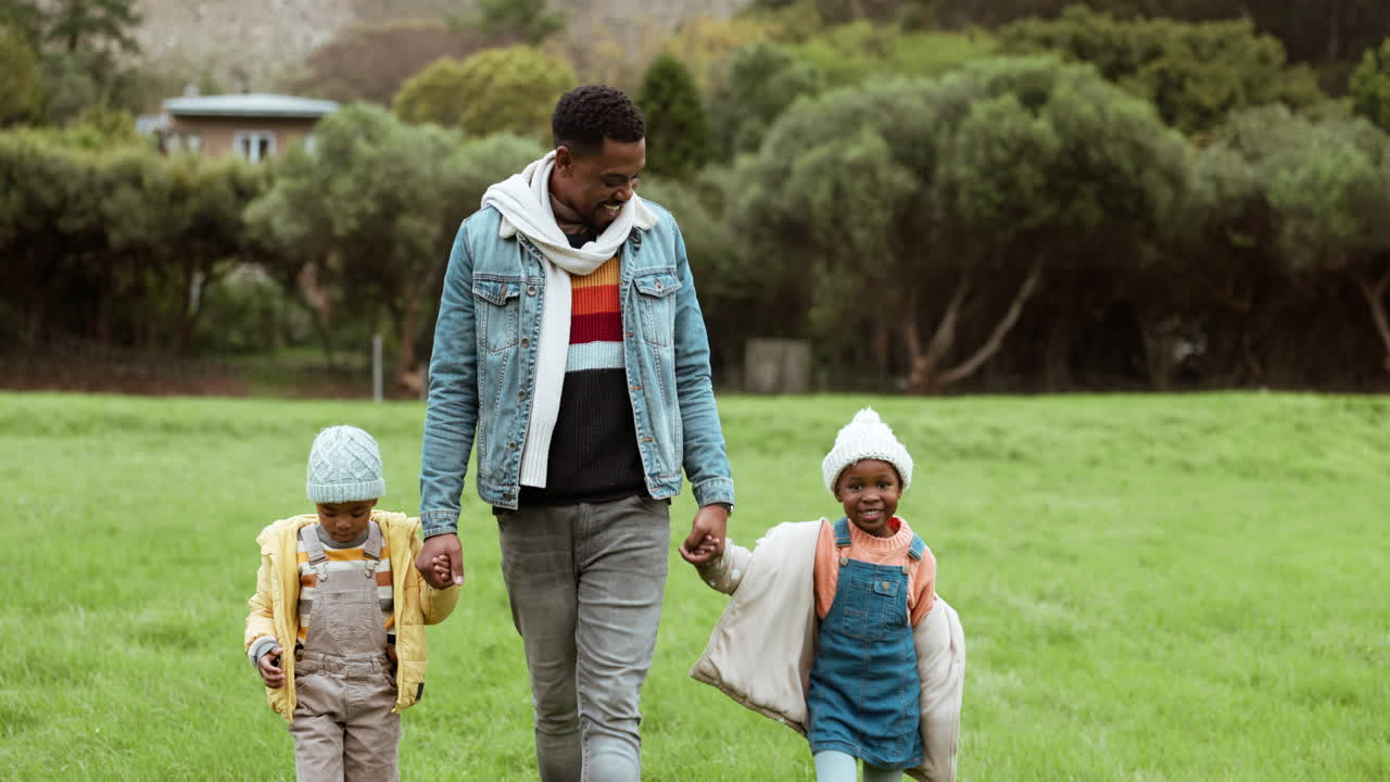 Papà a passeggio e bambini che si tengono per mano al parco