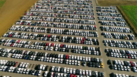 aerial footage of finished cars ready to be shipped on huge distribution center