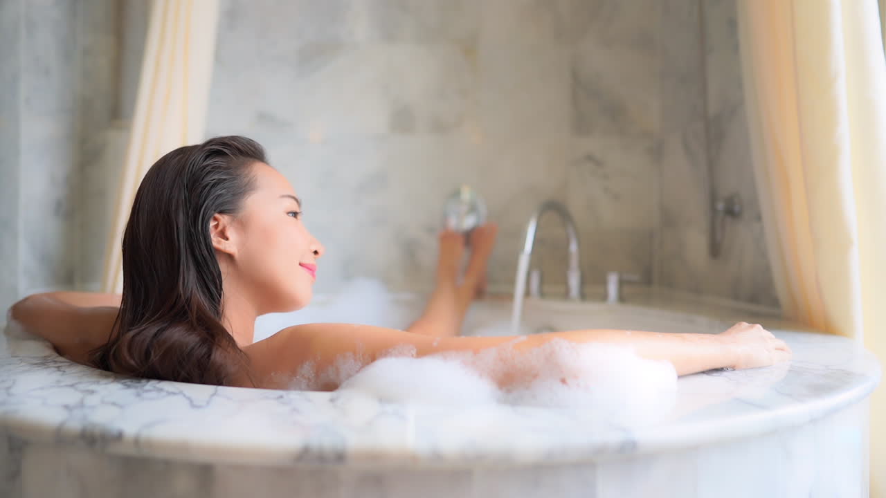 A sexy young woman lounges with her feet up in a bubble bath