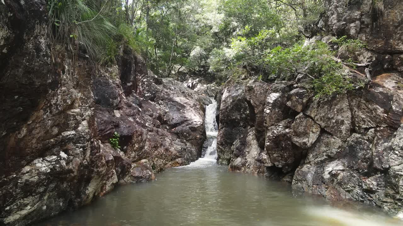 arroyo de selva tropical que desemboca en un pozo de natación privado y aislado en una roca.