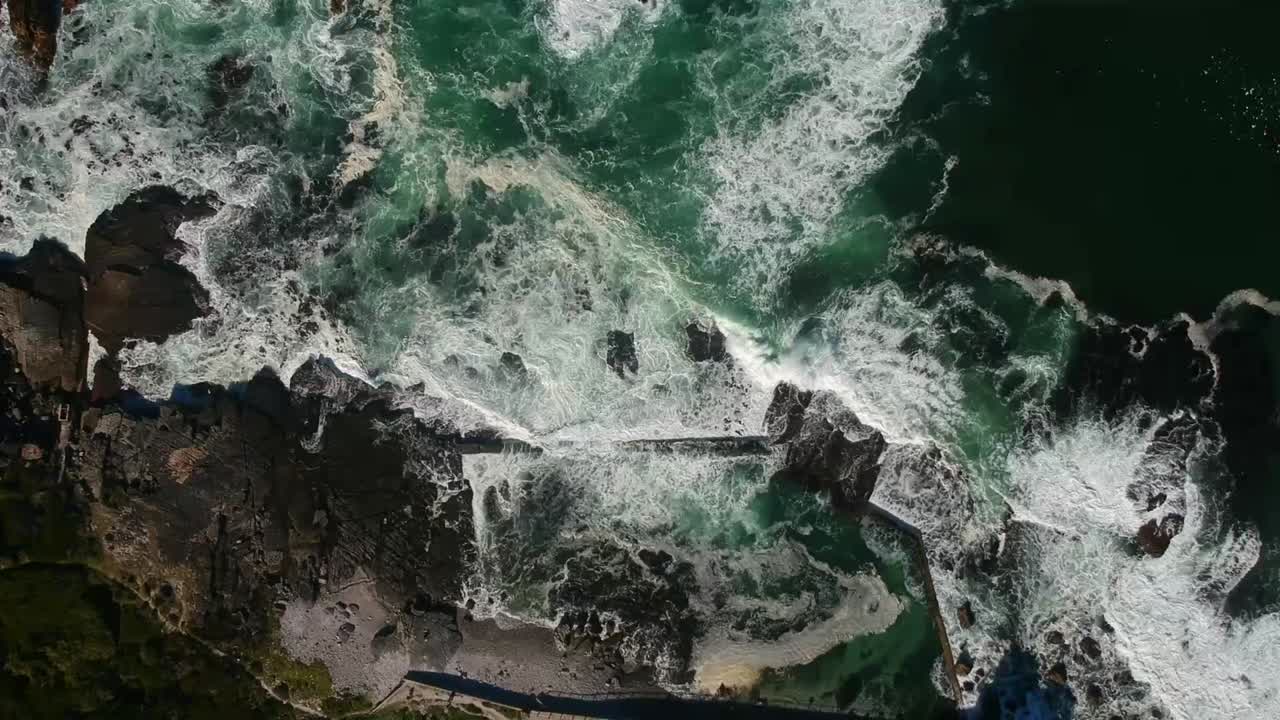 vista de drones de arriba hacia abajo de las mareas y las rocas, con las olas rompiendo