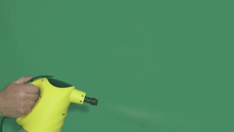 hand steam cleaner at work on green screen