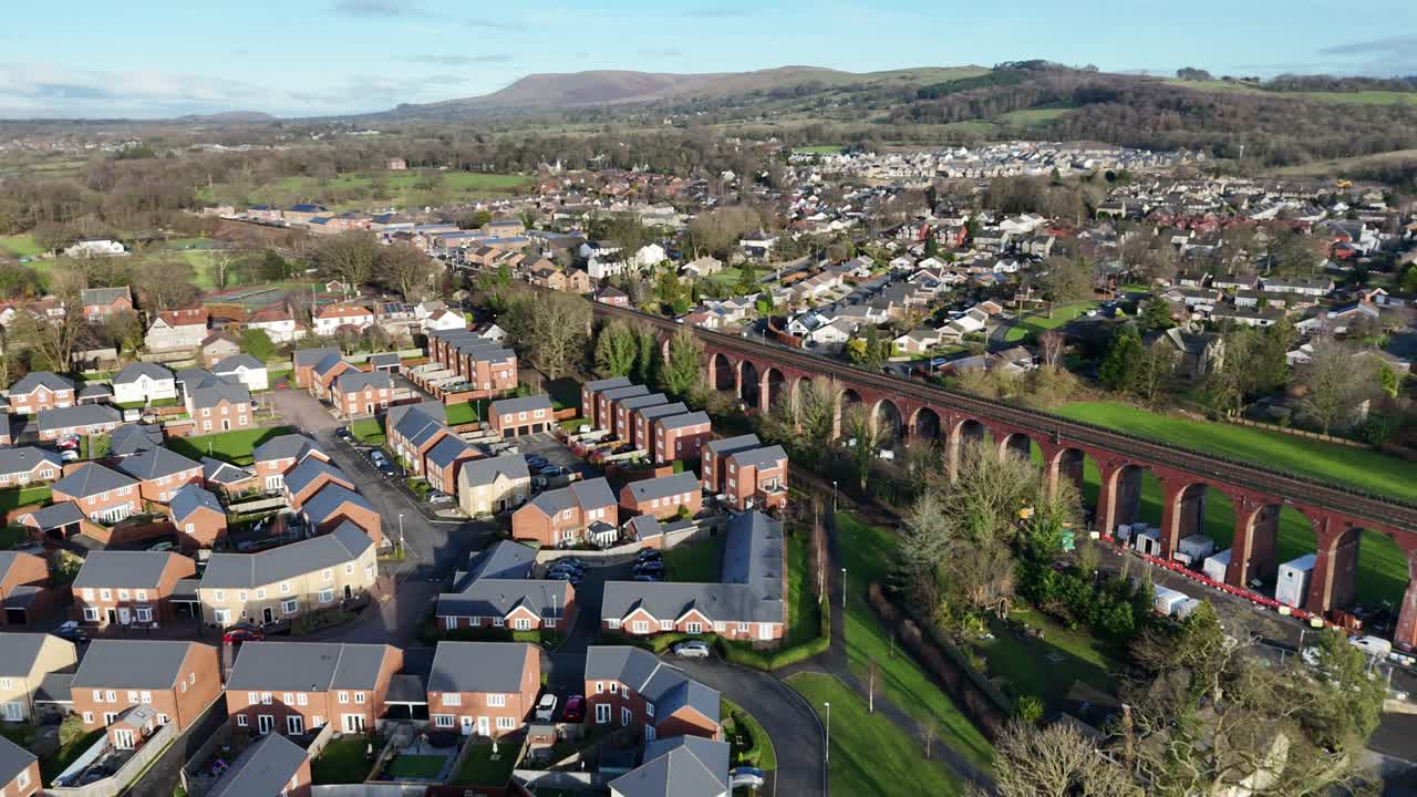Stunning aerial footage of Conisbrough Viaduct surrounded by quaint homes in South Yorkshire, England. The vibrant landscape, under clear skies, showcases architectural contrasts