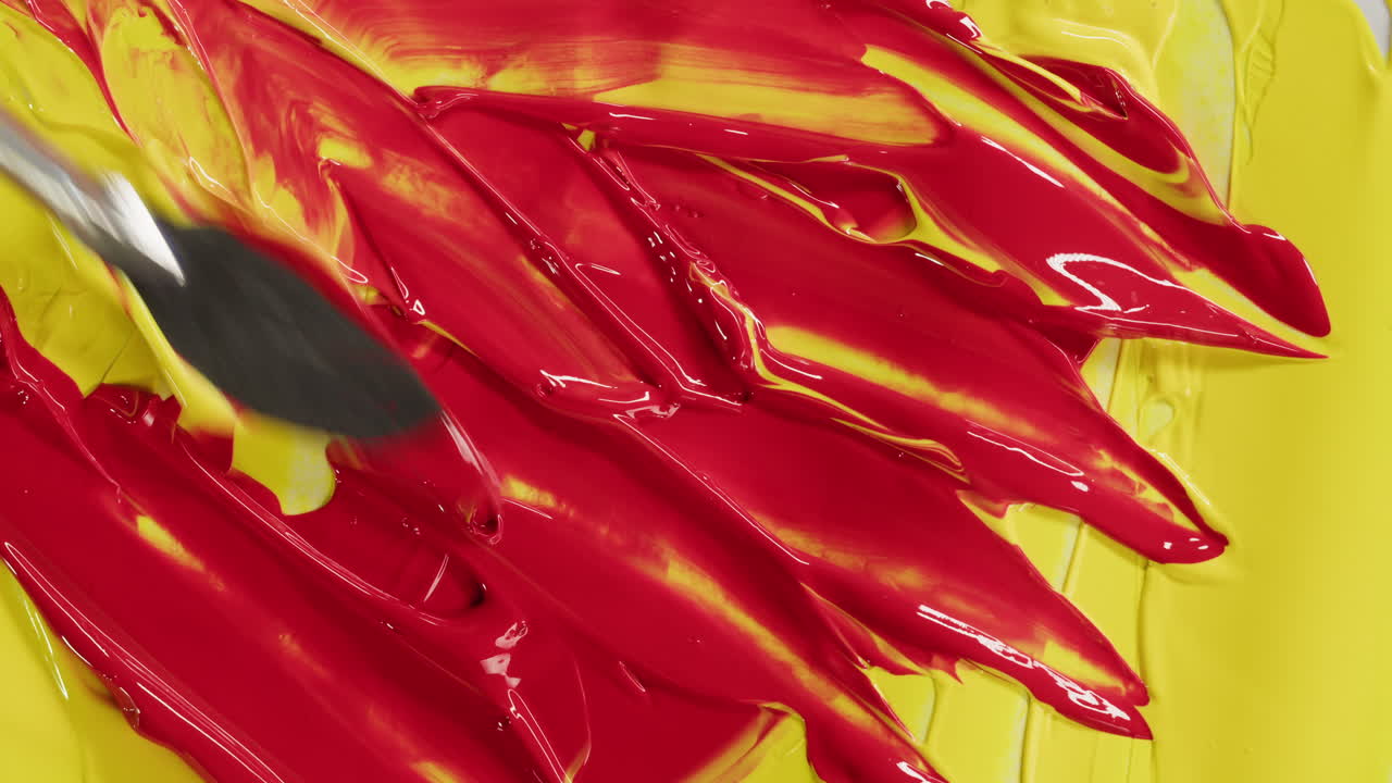 Spatola che stende pittura rossa vivace su superficie gialla