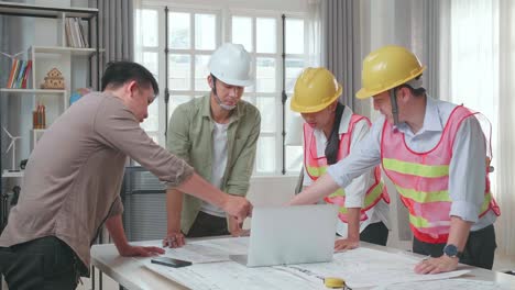 three asian engineers with helmets using laptop for working to a man at the office