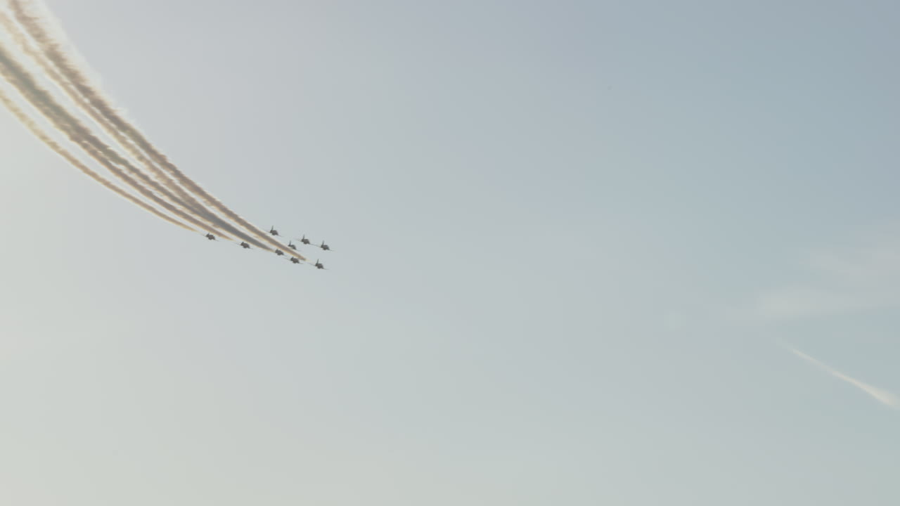 Jetfly, der flyver i formation med røgstriber på en blå himmel