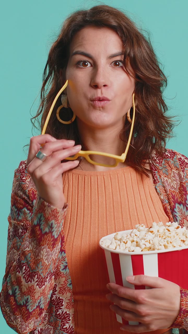 Donna con occhiali 3D che mangia popcorn e guarda online un film, una partita sportiva o una serie TV interessante