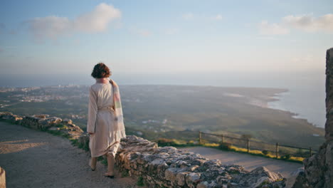 explorer standing high viewpoint overlooking distant coastline cityscape.