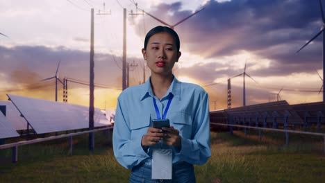 asian female with her smarphone with solar panel and wind turbines, she observes by looking around before she come to concentrating with her smarphone