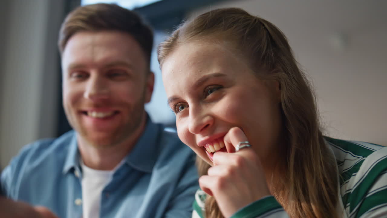 Closeup couple watching smartphone at living room together. Husband bonding wife