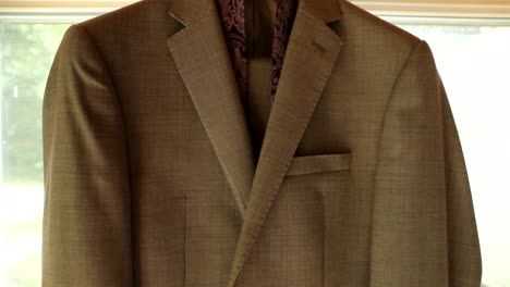 suit jacket and tie hanging in a beautifully lit room in preparation for a groom to get ready for a wedding