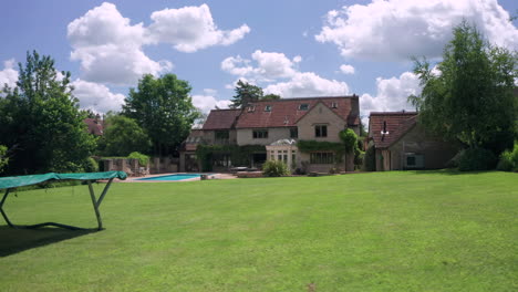 aerial orbit of a countryside home with trampoline and trees in foreground