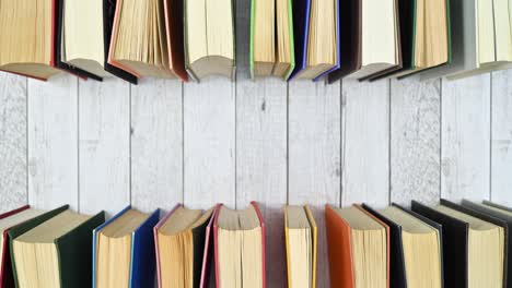 pile of vintage hardcover books move on top ad bottom of wooden theme. stop motion flat lay