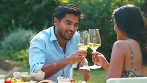 Pareja-Comiendo-Comida-Al-Aire-Libre-Y-Bebiendo-Vino-En-El-Jardín-De-Casa-Juntos