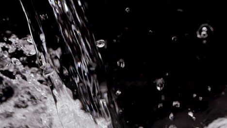Water-pouring-into-black-background-in-slow-motion-with-splashing-refreshing