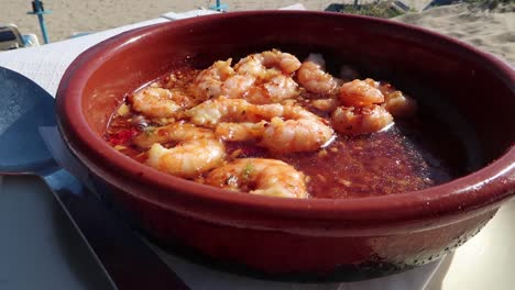 gambas tradicionales españolas pil pil en la playa en un clima soleado con vistas al mar en marbella, españa