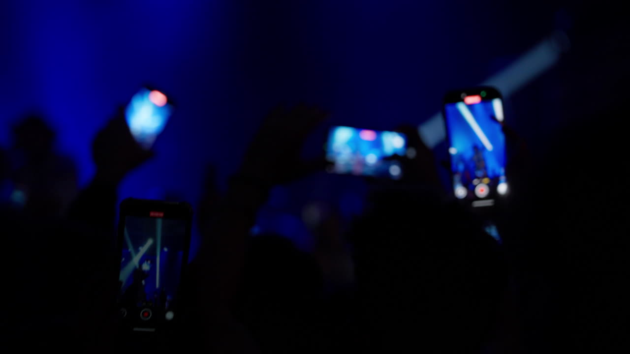 Livekonsert med publikum som filmer med smarttelefoner på et mørkt sted