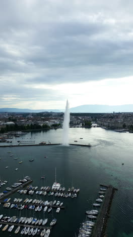 vertical, aerial: water fountain of geneva during the day (rade of geneva) in canton of geneva, switzerland, crane up drone shot