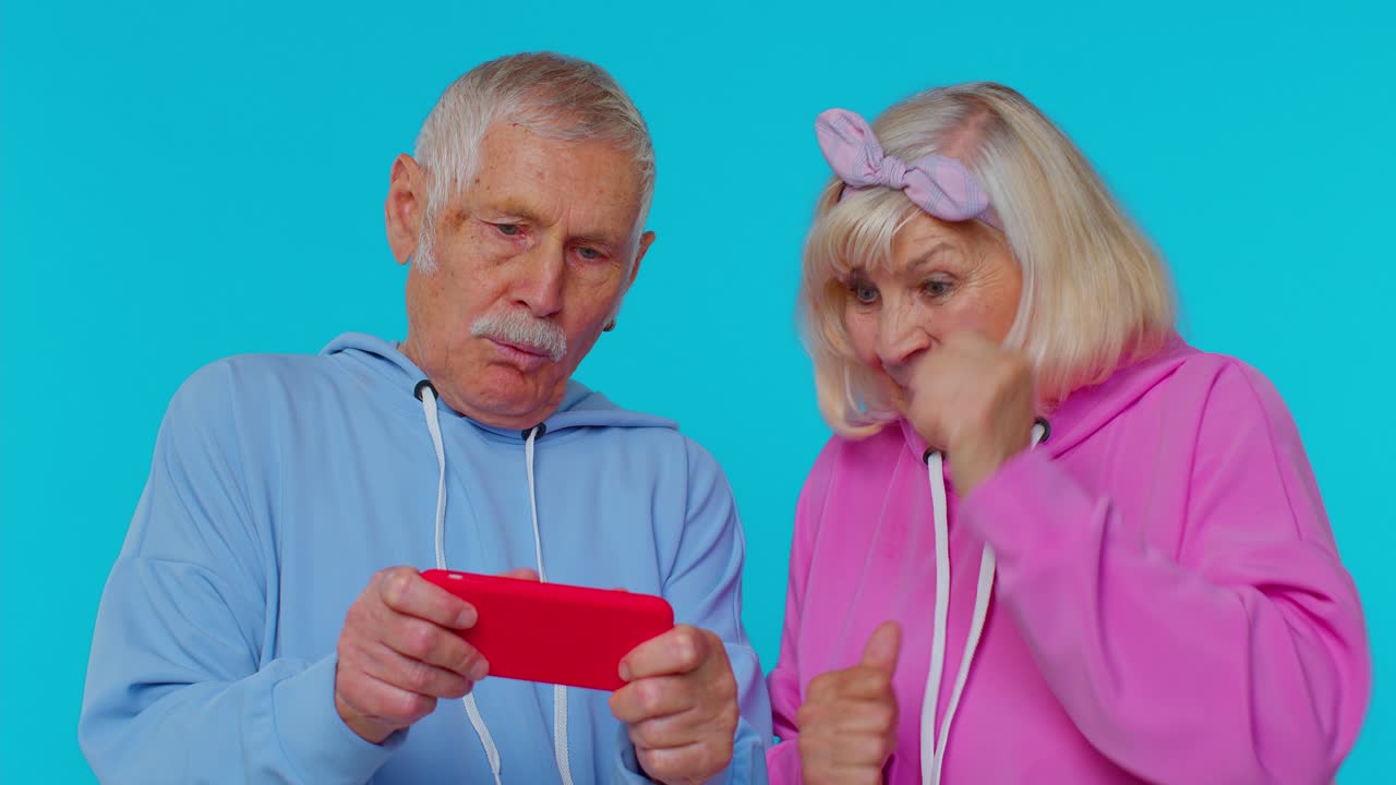 Preoccupato divertente nonno anziano nonna entusiasticamente giocando a giochi di corse sul telefono cellulare
