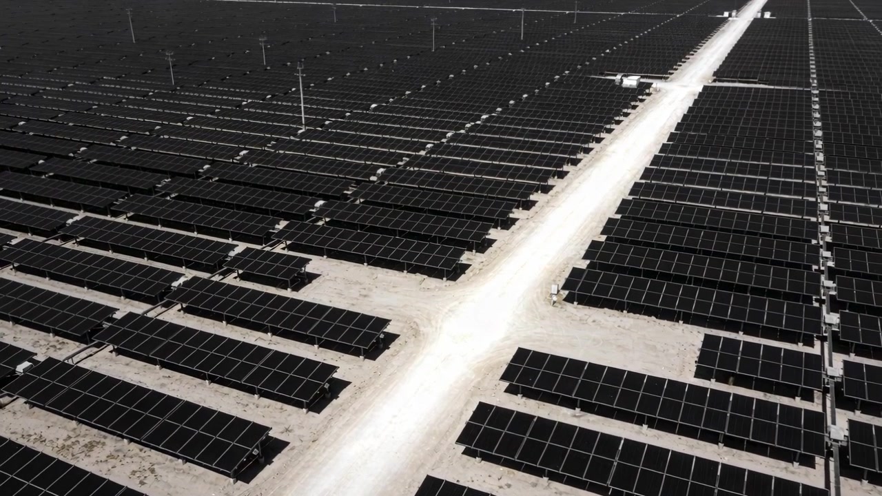 Rilevamento in corso, telecamera drone che si muove lungo una strada di servizio in un impianto fotovoltaico, mappando i pannelli solari.