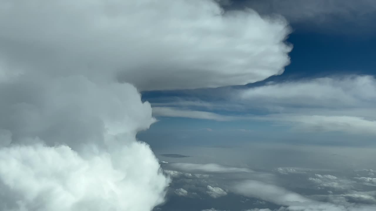 Immersive pilot POV FPV flying near the top of a huge perfect cumulonimbus storm cloud with an anvil shape. Aerial footage taken from the cockpit of a jet flying at cruise level. 4K 60FPS